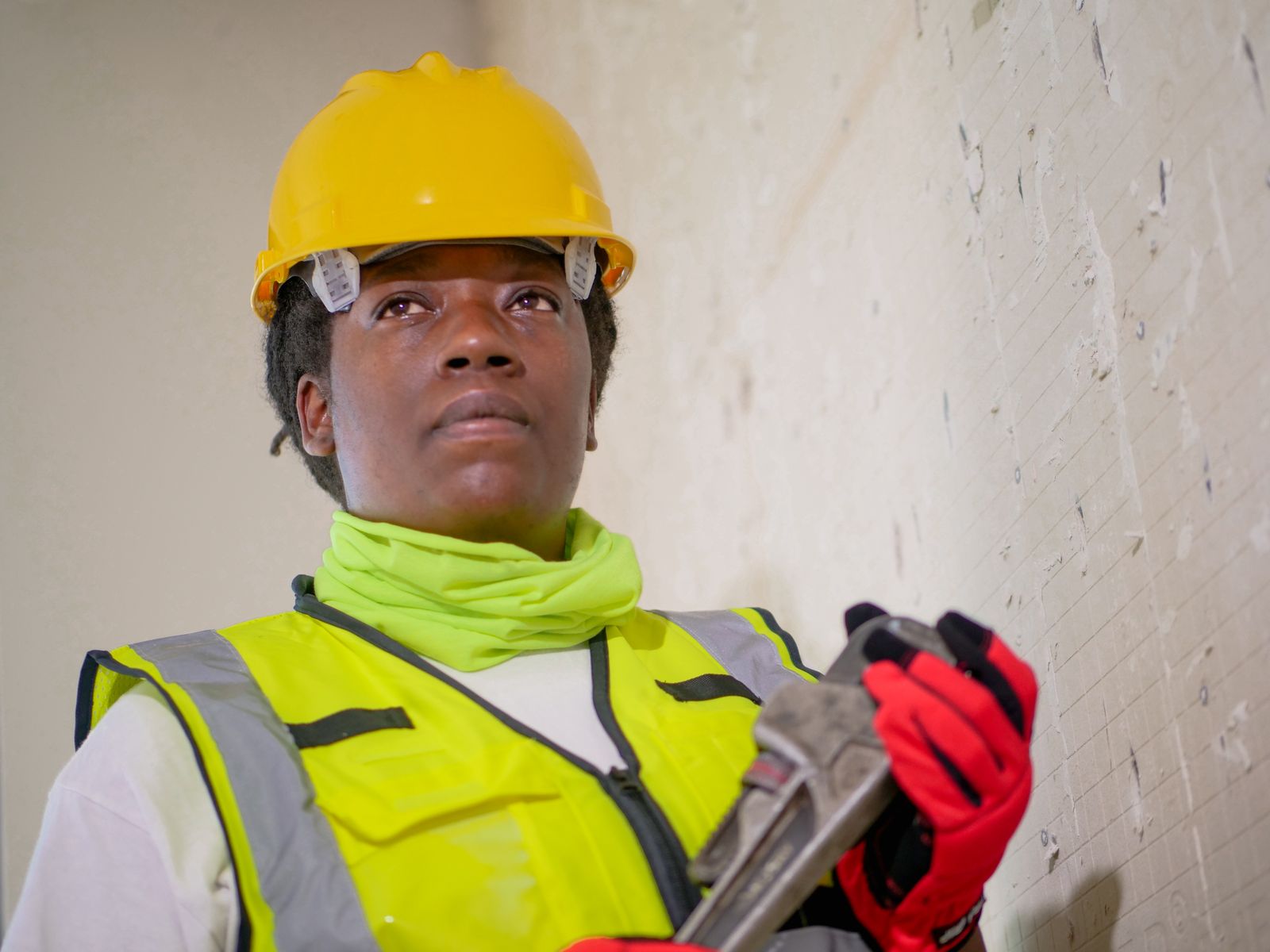 Plumber in safety gear holding a pipe wrench